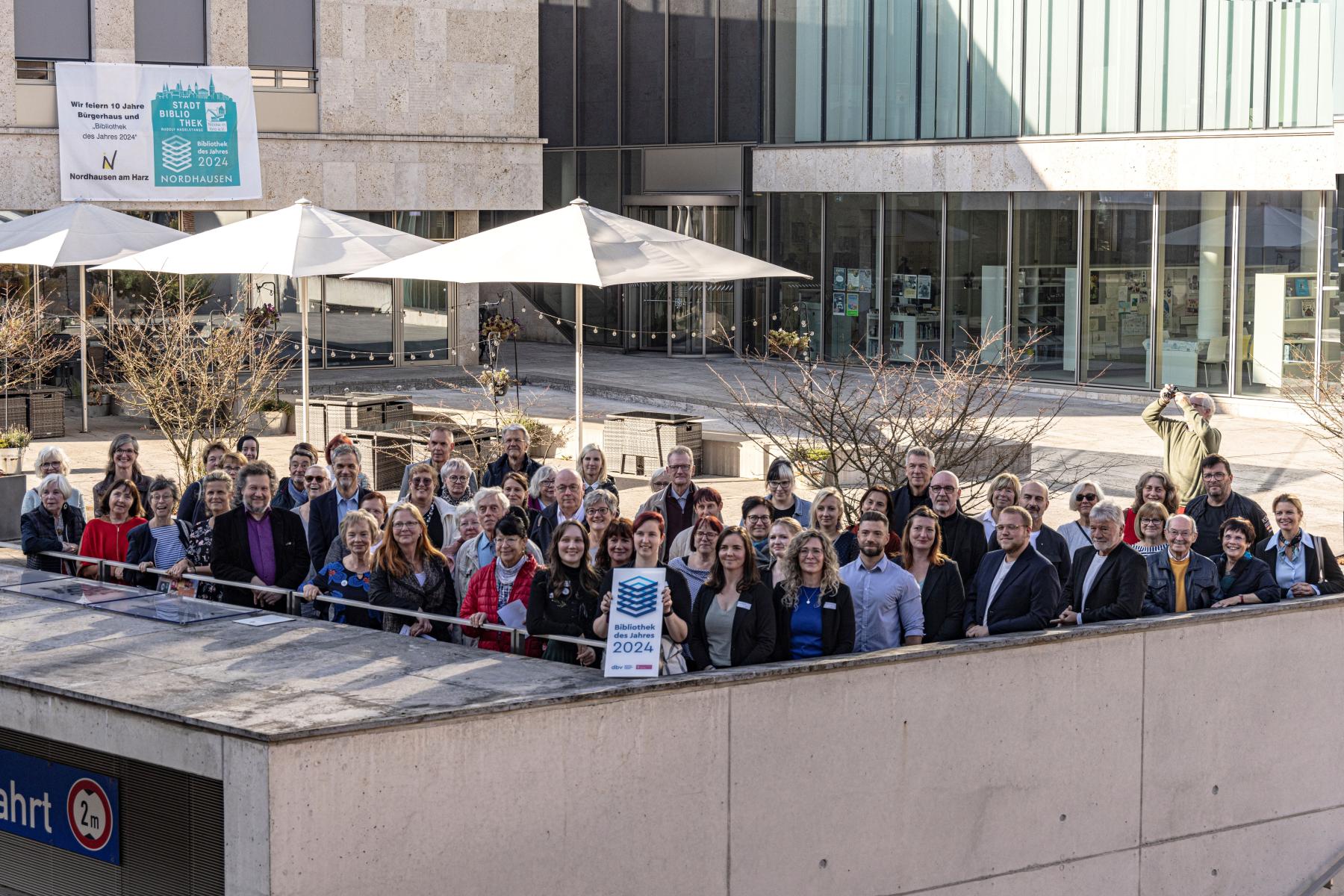 Gruppenfoto des Bibliotheksteams und aller Gäste der Verleihung mit der Plakette vor der Bibliothek