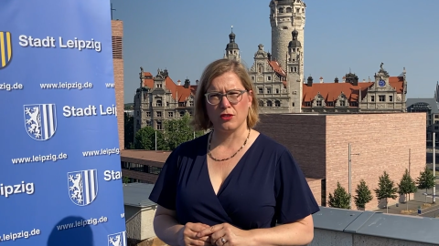Frau Dr. Skadi Jennicke, Bürgermeisterin für Kultur Leipzig, steht neben einem Roll-up der Stadt Leipzig mit der Stadt im Hintergund.